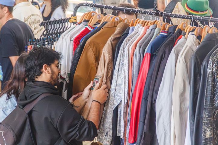 Visitante garimpando numa arara de camisas (julho de 2026)